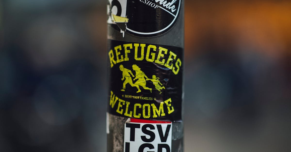 Street pole with stickers including 'Refugees Welcome', conveying a message of acceptance and solidarity.
